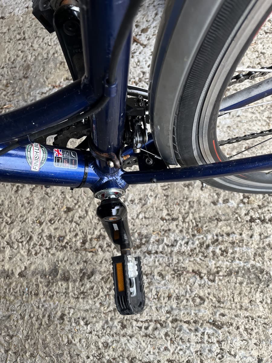 Close-up of a bottom bracket, crank and pedal on a blue bike